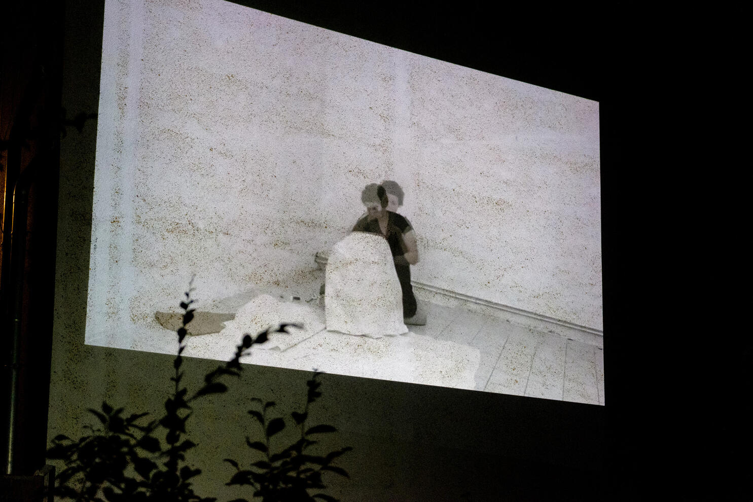 Videoprojektion eines Videos auf einer Häuserwand, Videotitel "Umschlossen"